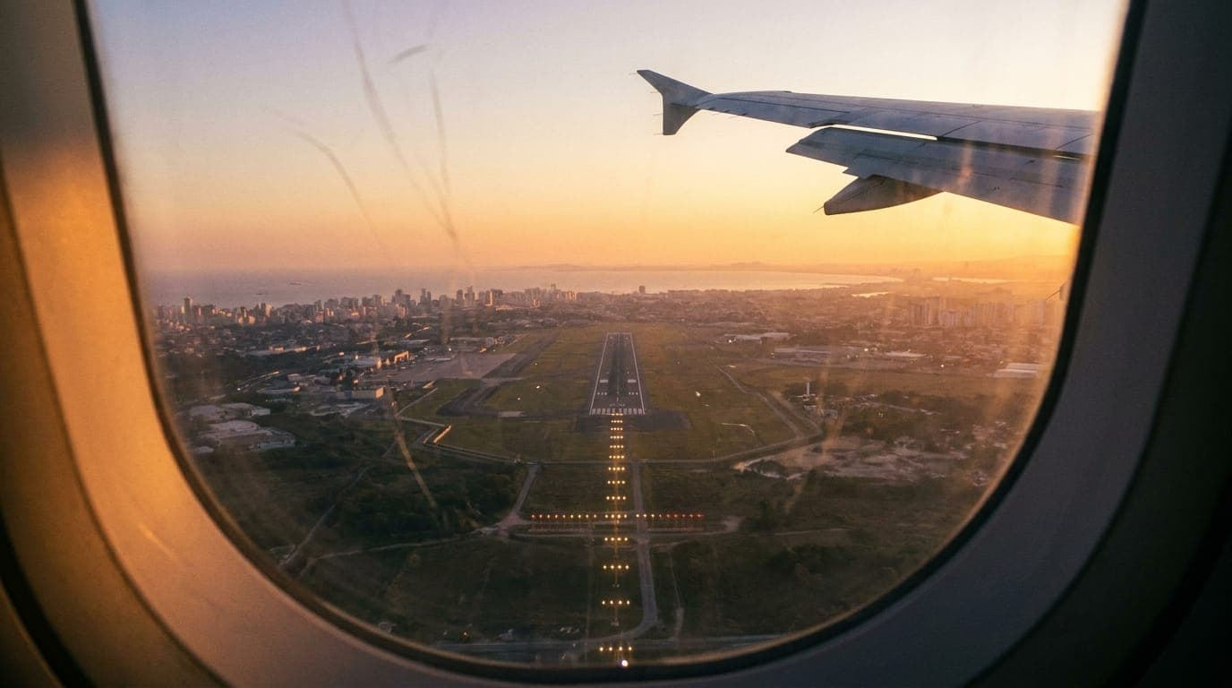 Pista de aterrizaje iluminada vista desde la ventanilla del avión al atardecer